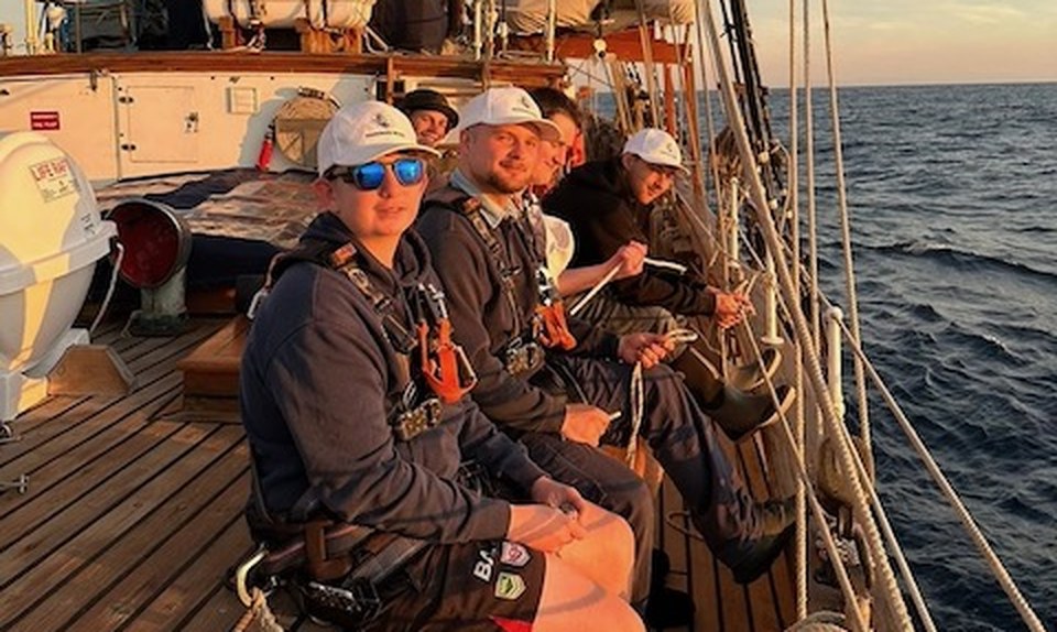 Riley Groves and fellow crew on deck at sunset aboard the Windeward Bound, 2025
